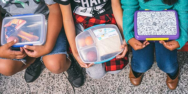Birds eye view of children sitting with lunch boxes full of food supplied by KidsCan