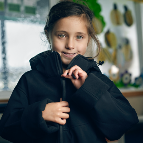 Young girl zipping up rain coat