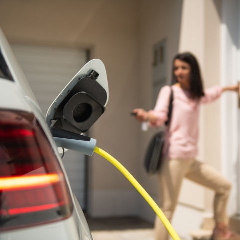 Electric car plan - a girl charging a car