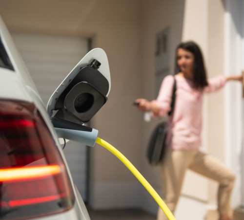Electric car plan - a girl charging a car