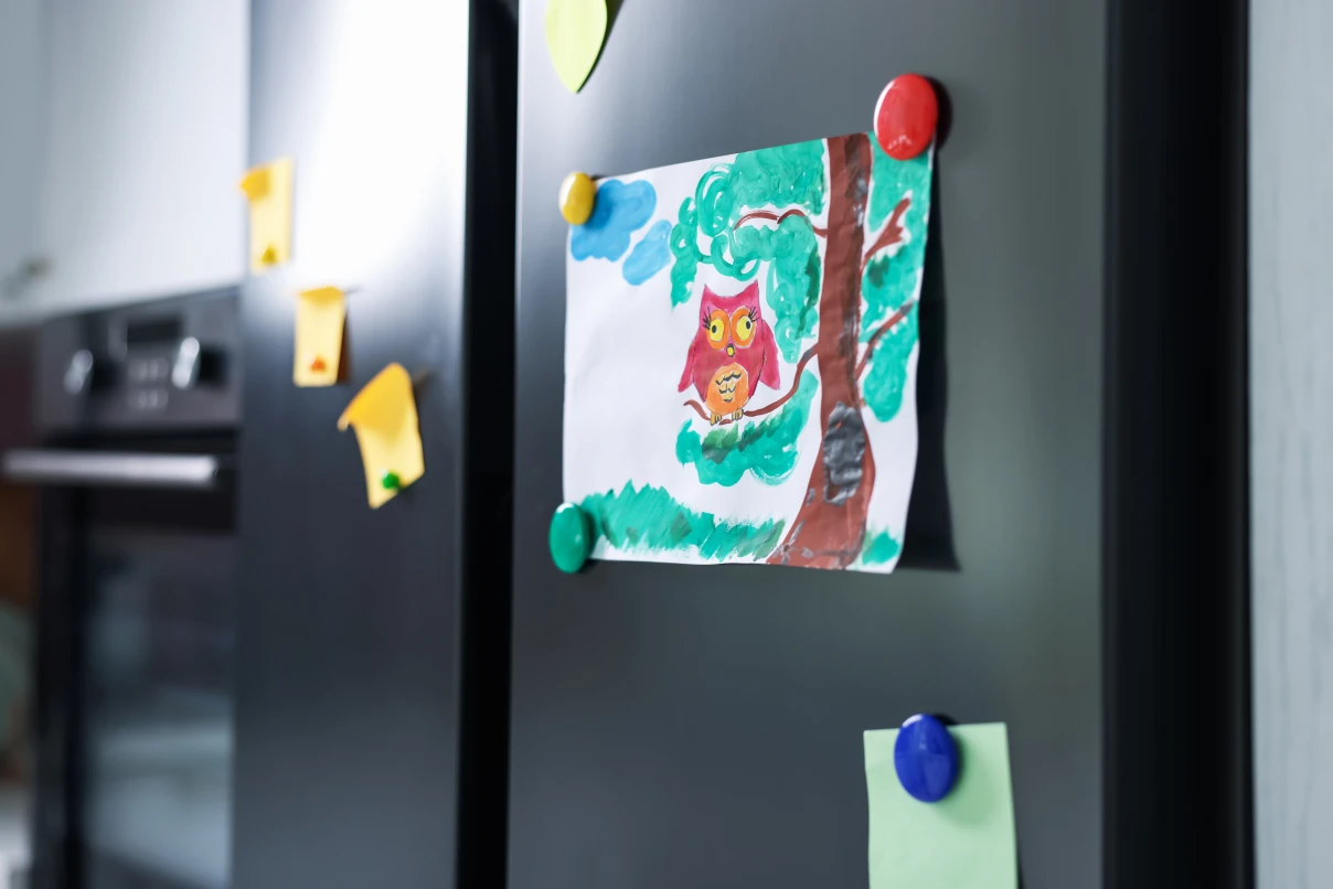 Refrigerator with child's drawing and magnets indoors, closeup