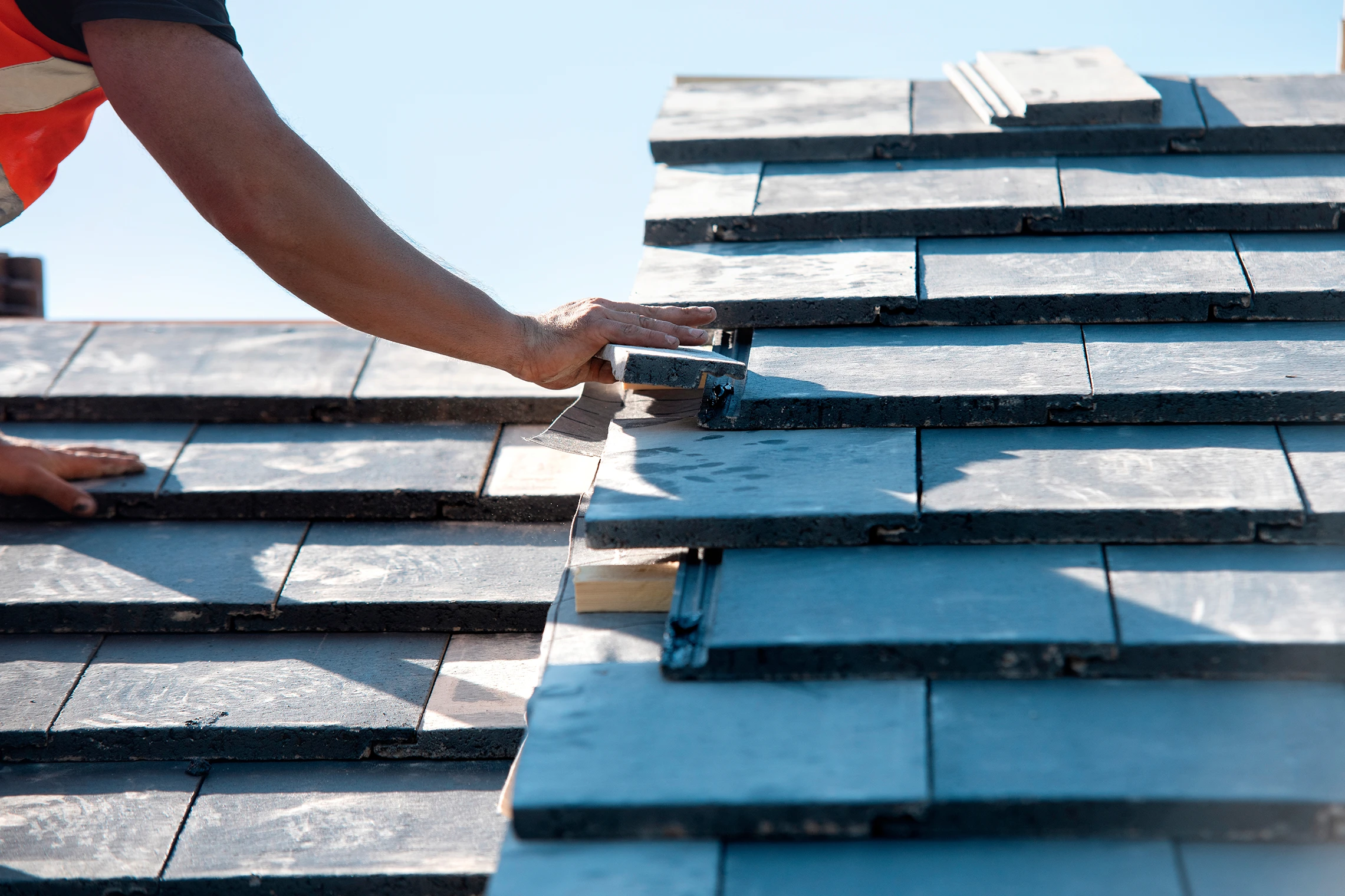 Close up of a mans hand as he places roof tiles.