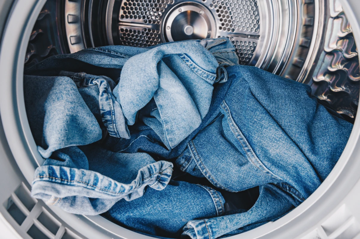 Blue jeans sitting in a dryer.