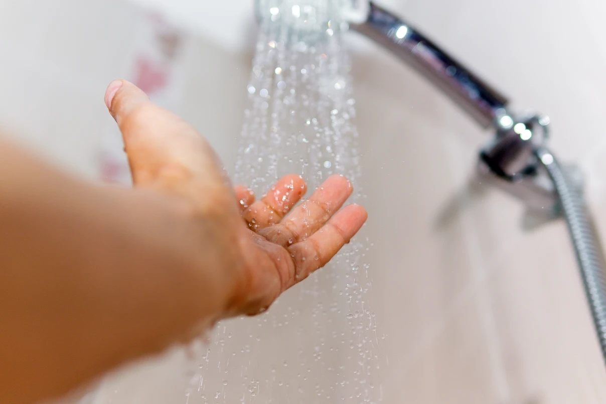 Hand under shower stream in bathroom