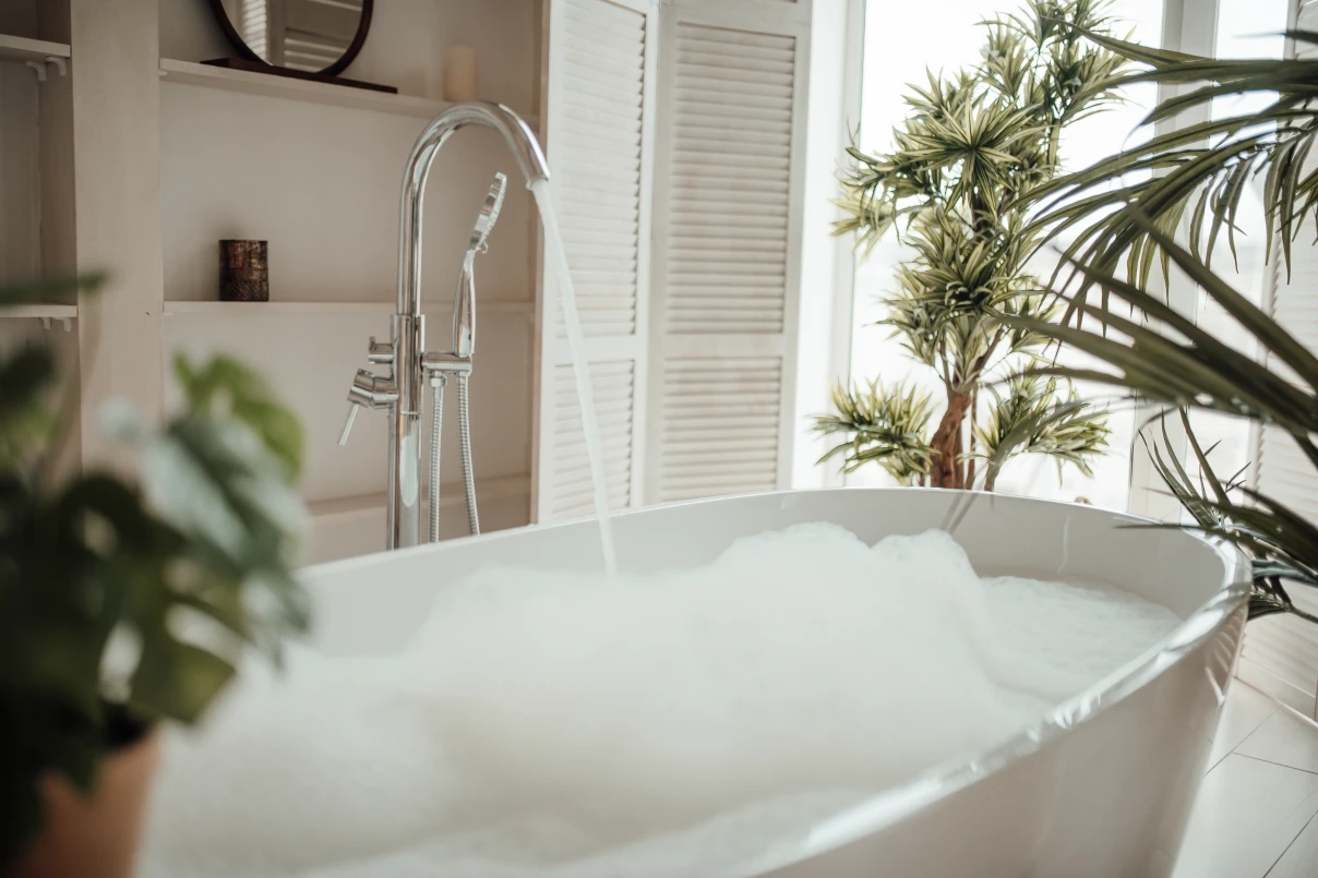 Bath in well lit room, filling with water and bubbles